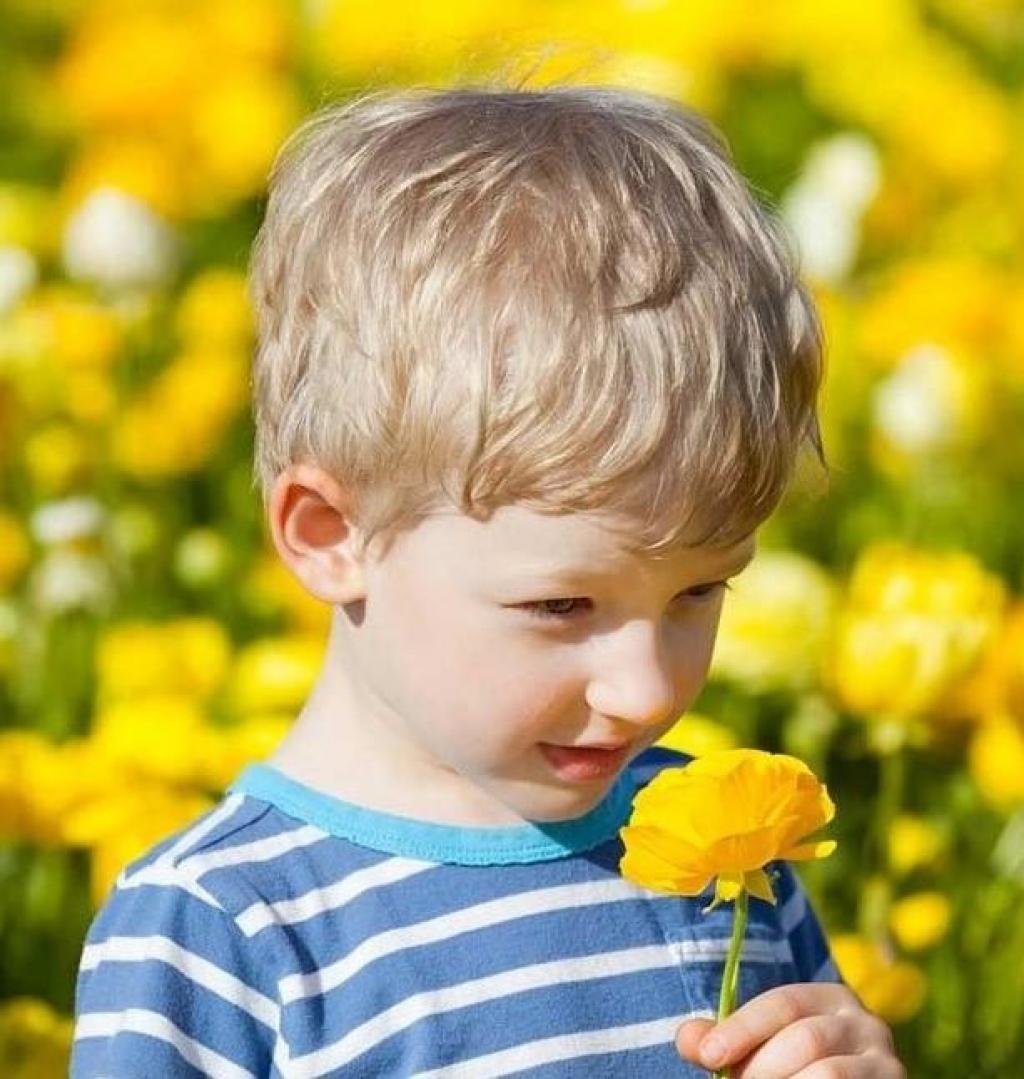 child smelling yellow flower
