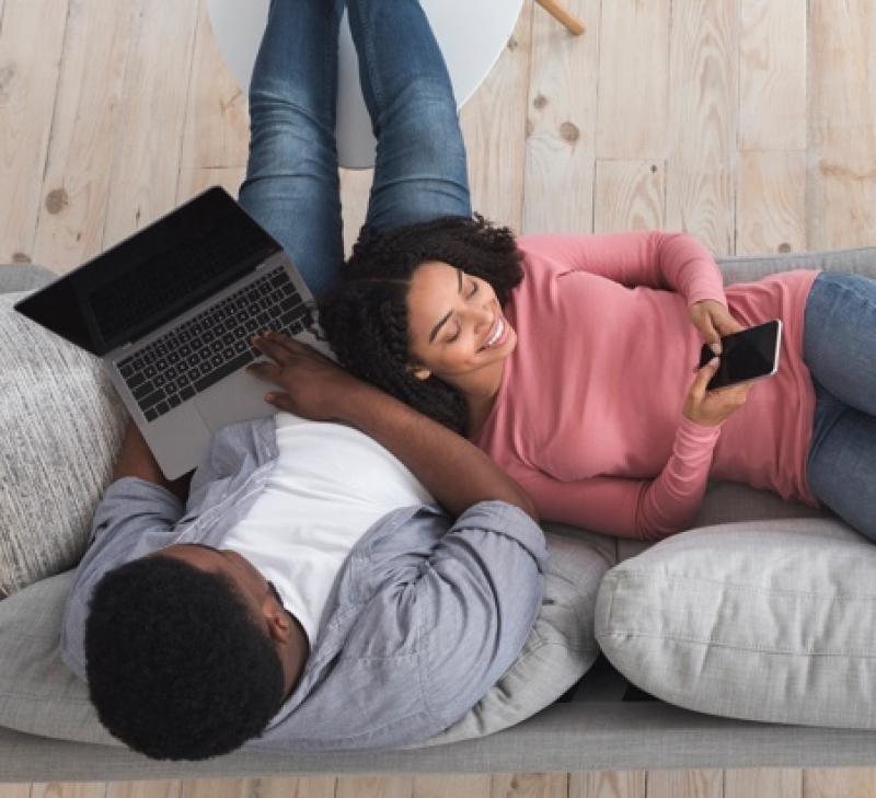 Couple on a couch with laptop and mobile phone